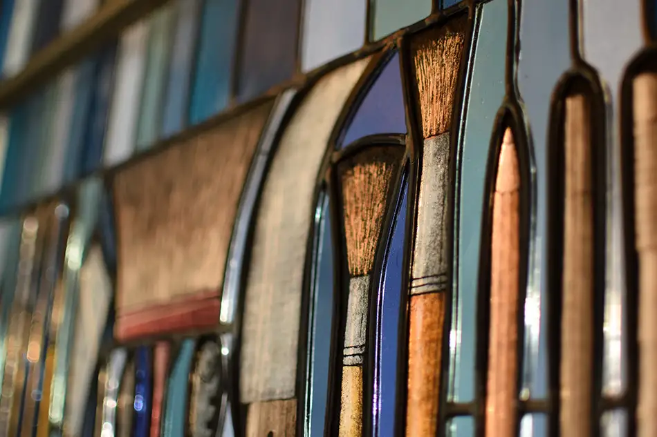 Stained glass window at Tiroler Glasmalerei with depictions of tools used in glass painting