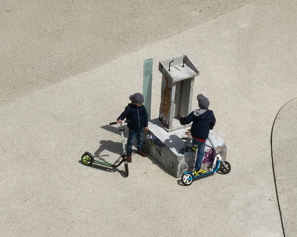 Dilapidated concrete lectern as art in public space with children at Landhausplatz Innsbruck