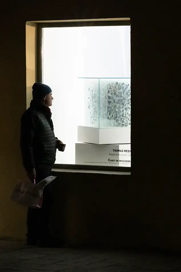 Anamorphic artwork - glass cube with four different images composed of image fragments - exhibition view with person - Foto by Daniel Jarosch